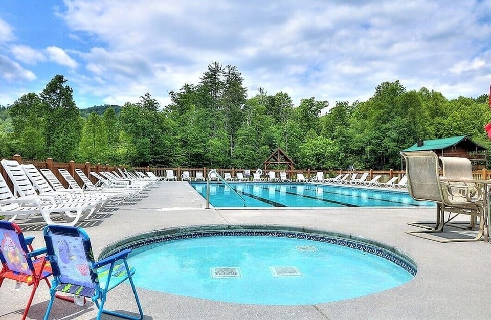 Complimentary access to the community outdoor swimming pool with lounge chairs and Smoky Mountain views at A Windy Ridge cabin in Wears Valley, Tennessee.