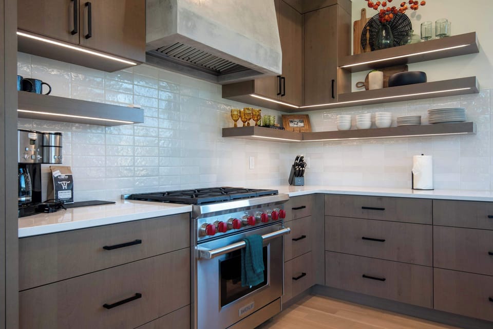 The kitchen behind the island — white subway tile, dark modern cabinetry, and a professional range ready for any meal