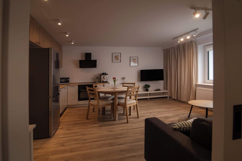 A spacious open-plan living area combines a modern kitchen with a dining set and a comfortable lounge corner.