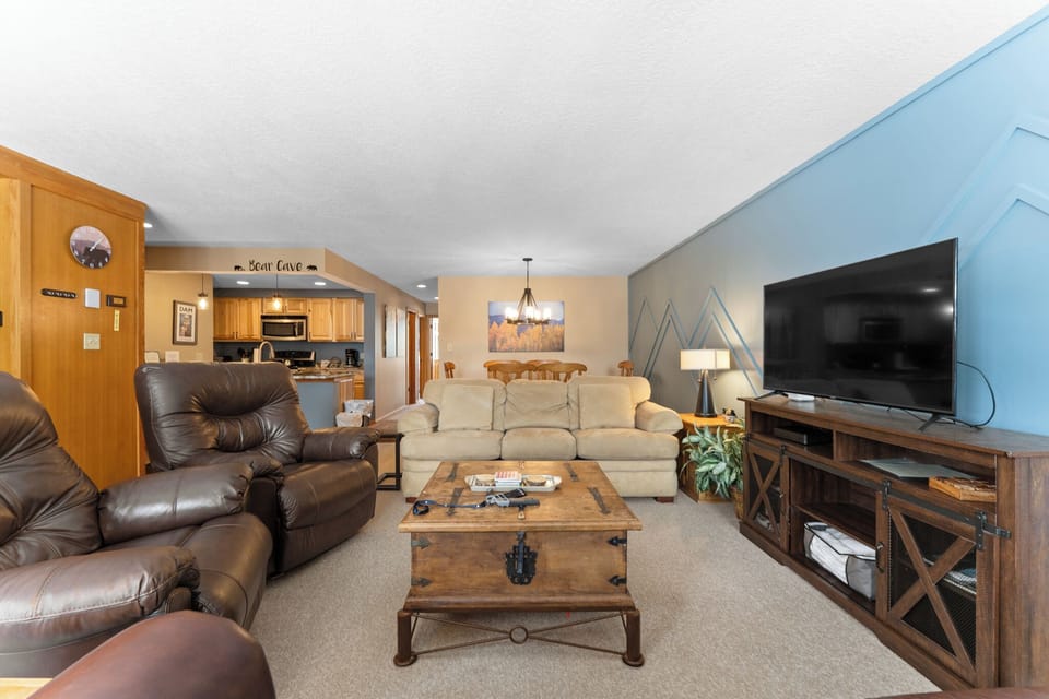 Living room with ample seating, wood-burning fireplace, TV, and queen sleeper sofa.