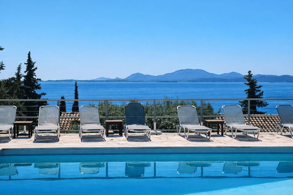 Beautiful swimming pool area with panoramic sea views and sun loungers, perfect for relaxing under the Corfu sun.