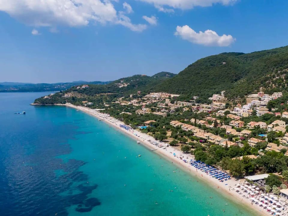 Aerial view of the stunning Barbati coastline, showcasing crystal-clear waters and lush green hills descending to the sea.
