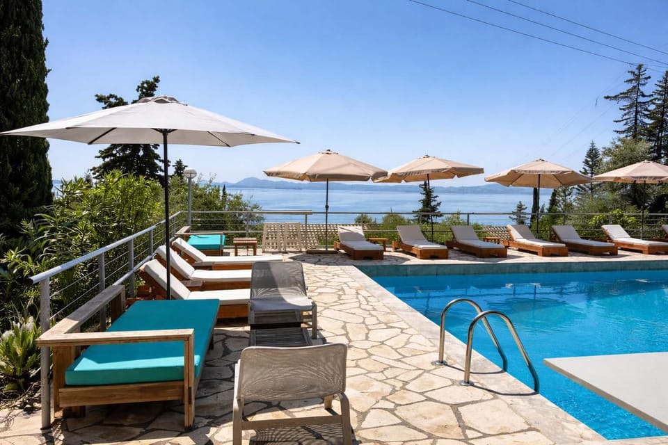Elegant pool terrace with sun loungers and umbrellas facing uninterrupted sea views. A tranquil space to unwind, soak up the sun, and enjoy the peaceful surroundings.