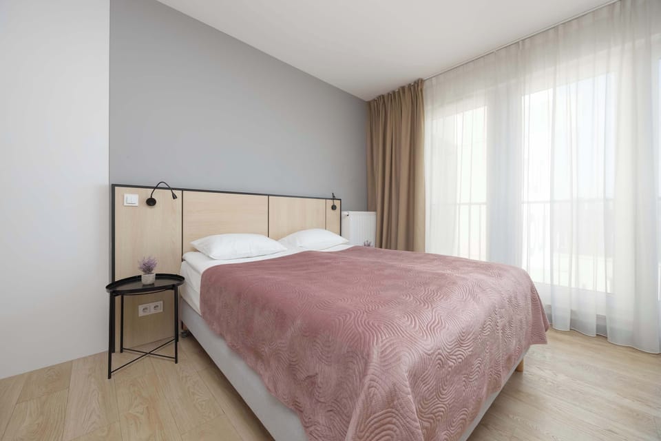 Bright studio space with a comfortable double bed positioned near large windows, creating an airy and welcoming atmosphere.