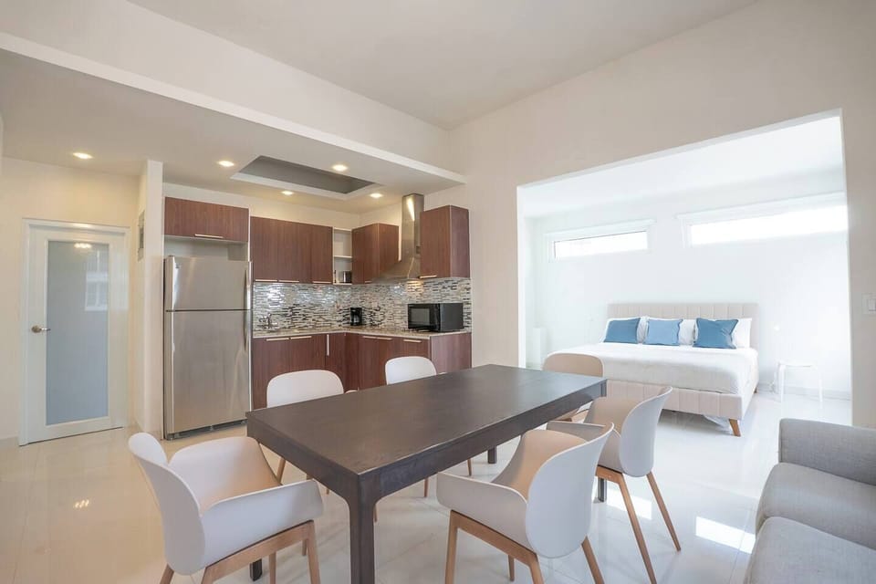 The sleek, modern kitchen opens up to the dining space, with a view into one of the serene bedrooms.