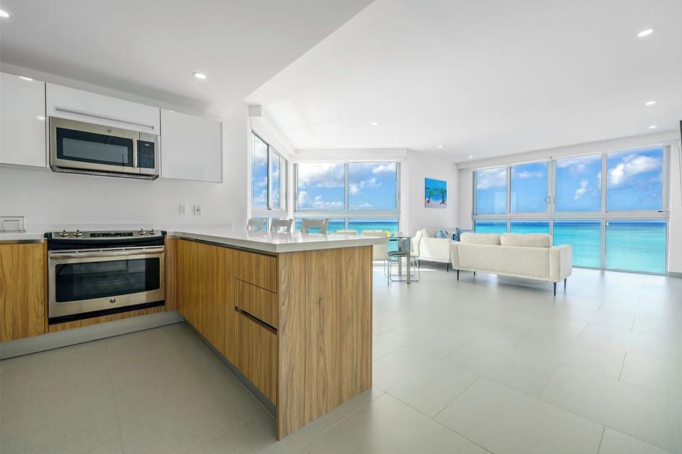 Modern open kitchen flows into your bright living space with stunning ocean views through floor-to-ceiling windows.
