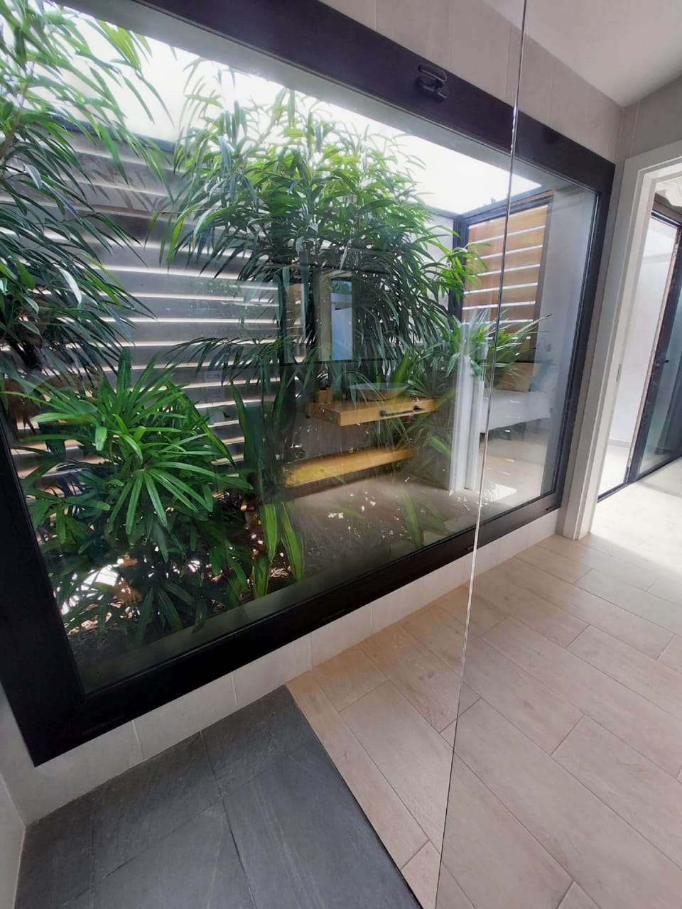 Bedroom 2 bathroom – A serene space with a walk-in shower and lush greenery for a relaxing ambiance.