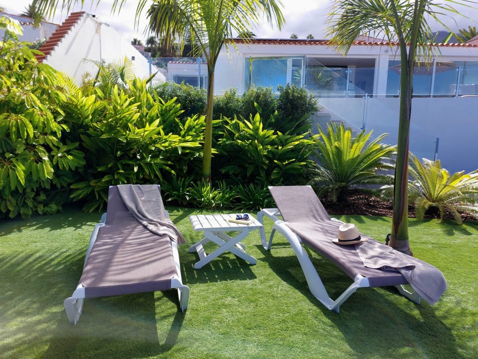 Tropical garden retreat – Relax on sun loungers surrounded by lush greenery in a peaceful paradise.