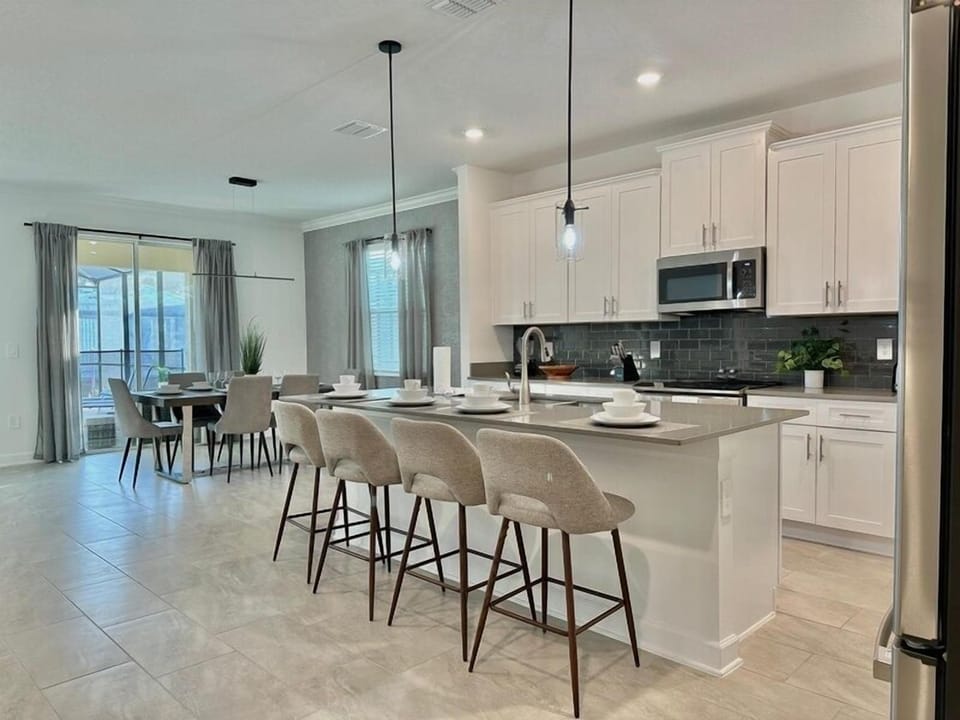 Your modern kitchen flows seamlessly into the dining area, featuring sleek white cabinets, granite countertops, and stylish bar seating perfect for casual meals.