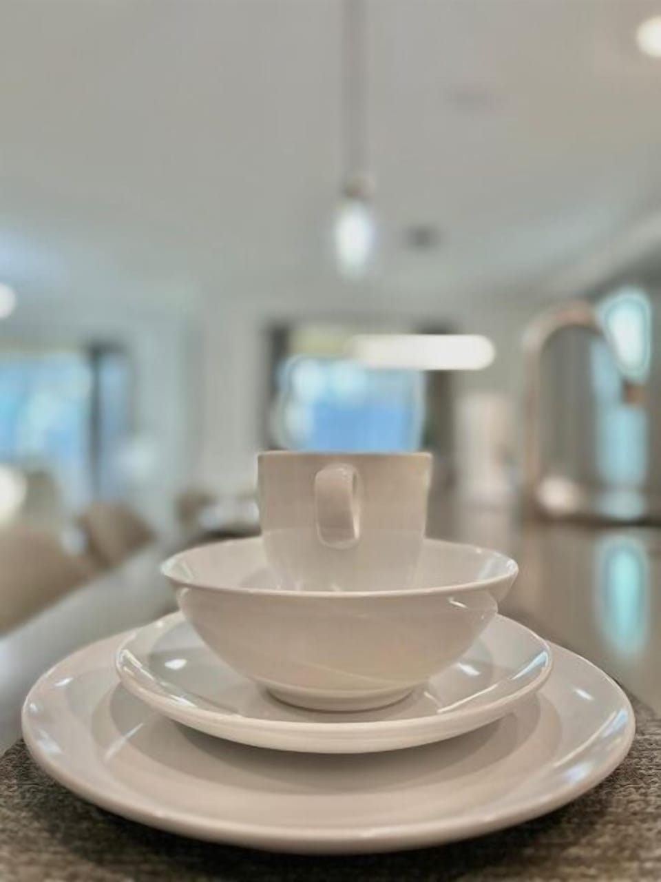 Start your mornings with elegant white dinnerware perfectly placed for your enjoyment in this bright, modern space.