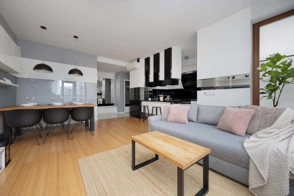A wide-angle interior view captures the transition from the dining table to the comfortable seating area. The layout is functional and open, making the apartment feel larger.