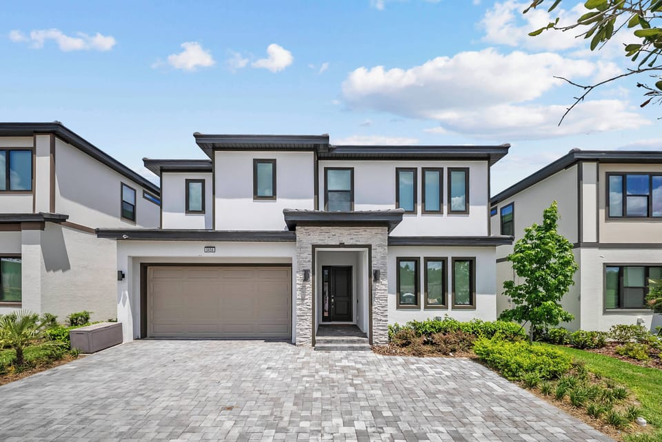 Experience a stylish exterior with a blend of stone and sleek siding, large windows that invite natural light, and charming landscaping. The paver driveway creates a warm welcome, ideal for relaxation and outdoor enjoyment.