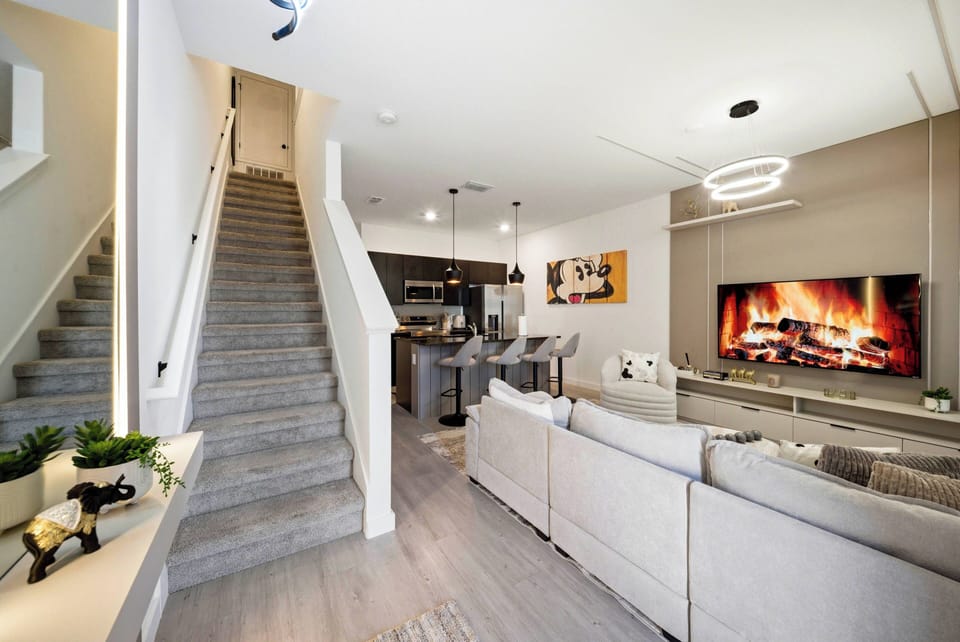 Welcome to a warm living area featuring soft beige tones and a spacious layout, complete with a stylish sectional and modern fireplace. The sleek kitchen nearby makes entertaining or unwinding after your adventures a breeze.