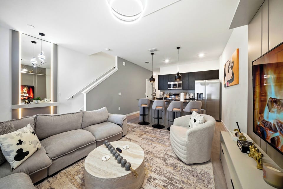 Unwind in a stylish living area with a plush gray sectional and cozy chair, perfect for relaxing after your adventures. Contemporary lighting enhances the sleek kitchen and inviting bar seating, ideal for socializing with friends.