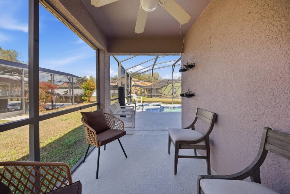 Step into a cozy screened porch featuring stylish wicker chairs that invite you to unwind while enjoying the gentle breeze. Large windows frame a refreshing view of the pool area, creating a sunlit ambiance perfect for relaxation.