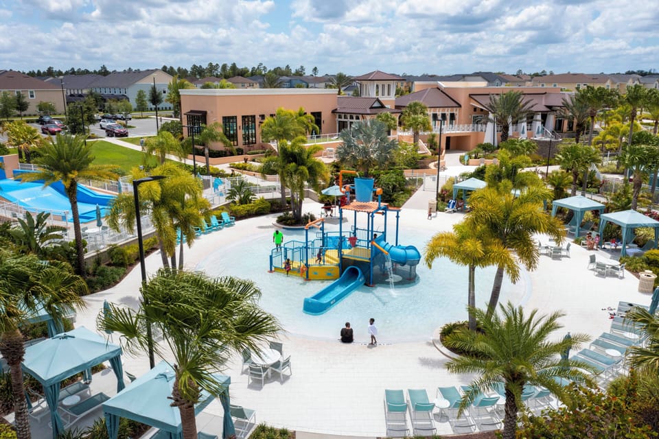 Welcome to a vibrant oasis featuring colorful water elements and shaded lounges for relaxation. The bright splash pad, nestled among lush palm trees, provides families with a delightful escape, while the pristine pool invites.