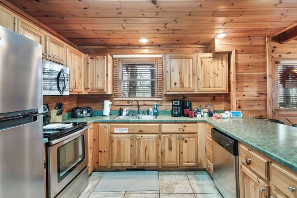 Step into your rustic cabin kitchen with warm wood walls and ample counter space for preparing mountain meals together.