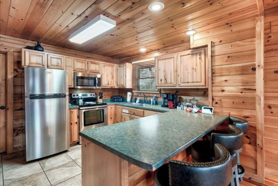 Your cabin kitchen blends rustic charm with modern convenience, featuring stainless appliances and cozy wood warmth for memorable meal prep.