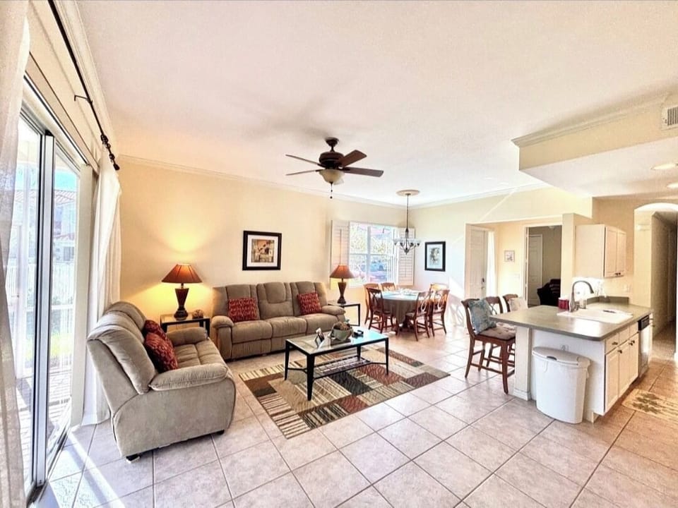 Relax in your spacious open-concept living area with plush seating, modern kitchen island, and warm natural light streaming through large windows.
