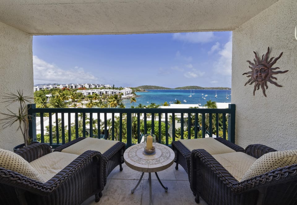 Covered balcony with comfortable lounge chairs and side table  overlooking Cowpet Bay.