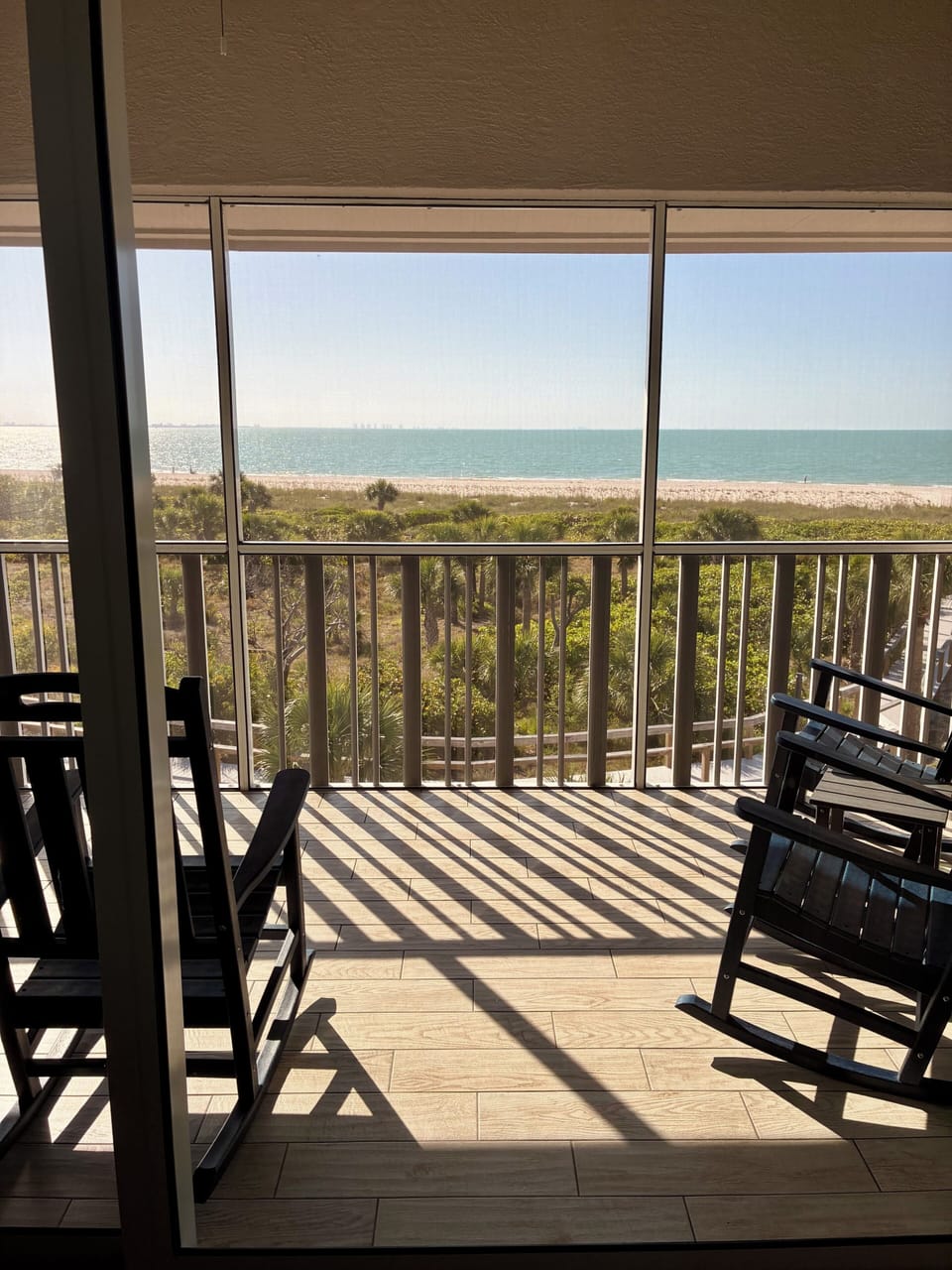 Screened lanai has 4 rocking chairs and a clear view of the Gulf