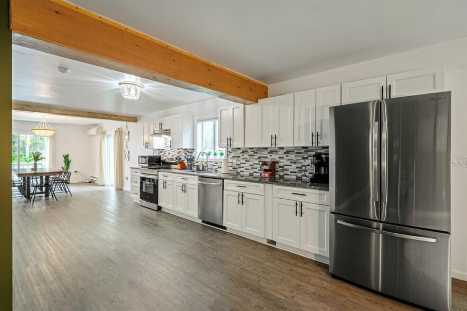 Cook with ease in this fully equipped kitchen, featuring sleek stainless steel appliances including a fridge, oven, stove, microwave, and dishwasher—everything you need for a seamless culinary experience.
