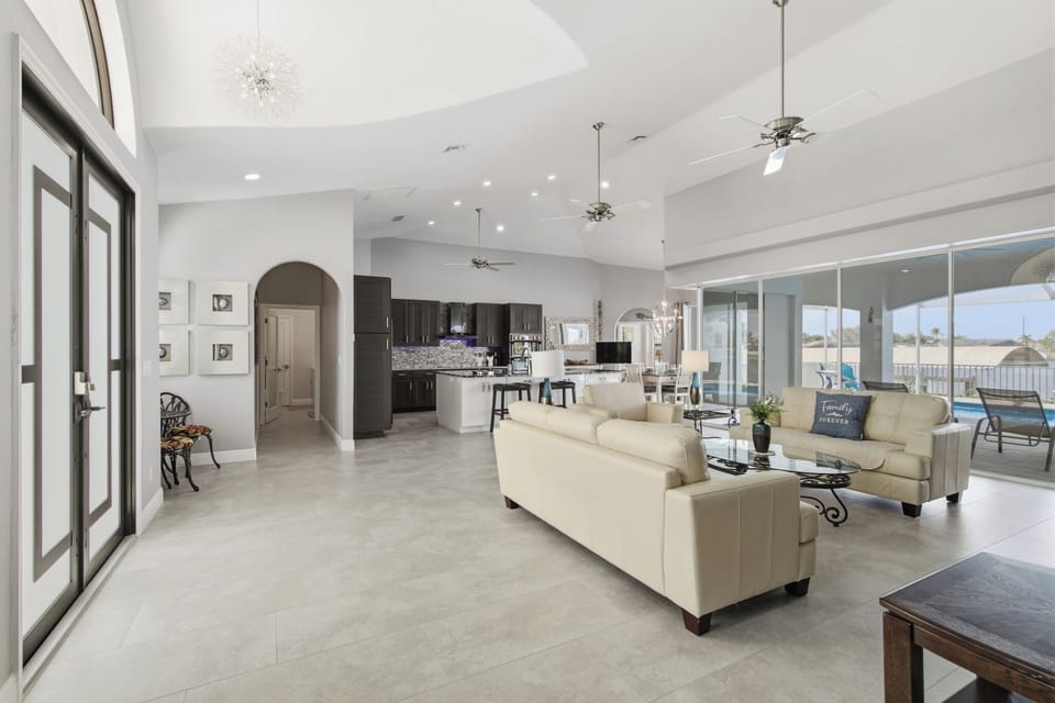 Spacious open-concept living room and kitchen with high ceilings, modern furnishings, and view through to the outdoor area