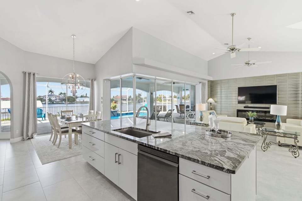 Second kitchen or kitchenette area with white cabinetry, granite island, and views of the canal through full-length windows