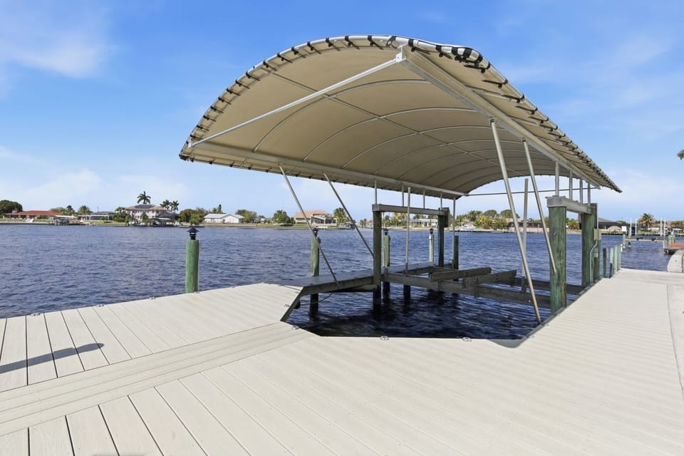 Private covered boat dock and lift on the canal with a large canopy, pilings, and open water views