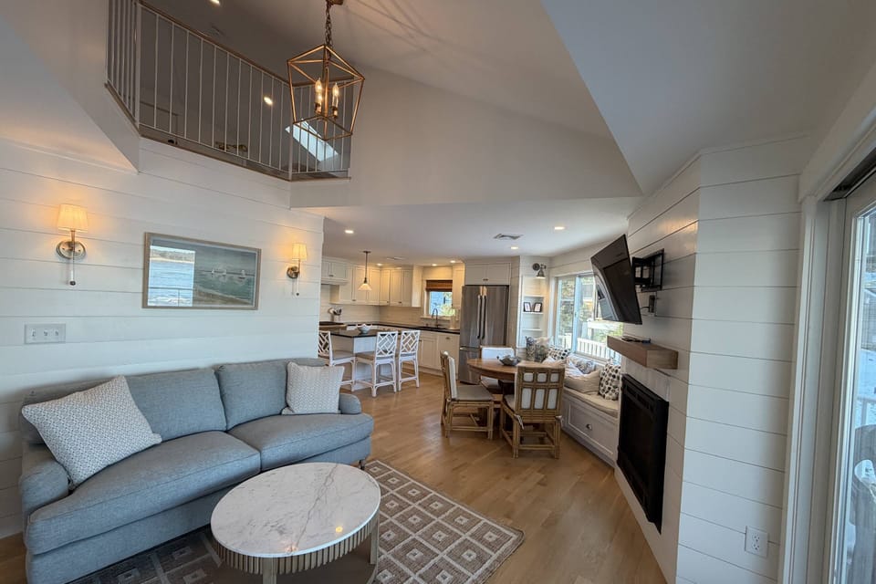 View of the living room with smart TV and gas fireplace, breakfast nook, large fully-equipped kitchen and upstairs loft with 2 twin beds