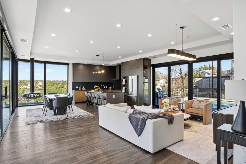 Open-concept living meets designer kitchen—steps from the pool through wall-to-wall glass.