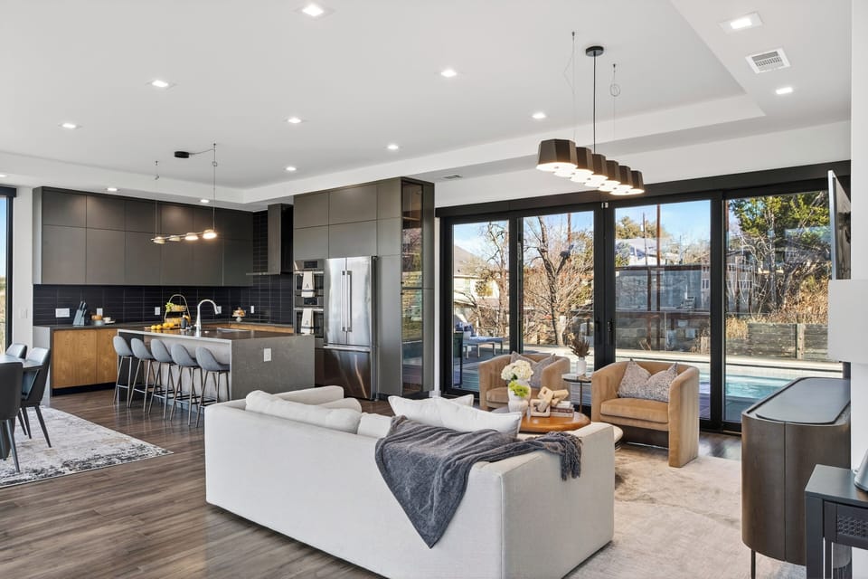 Open-concept living meets designer kitchen—steps from the pool through wall-to-wall glass.