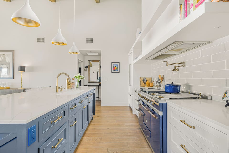 A view down the galley-style kitchen showing the blue cabinetry and premium appliances.