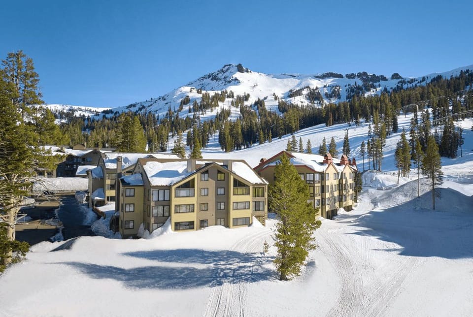 Embrace the cozy charm of snow-laden condos nestled against the majestic winter landscape, inviting adventure at your doorstep.