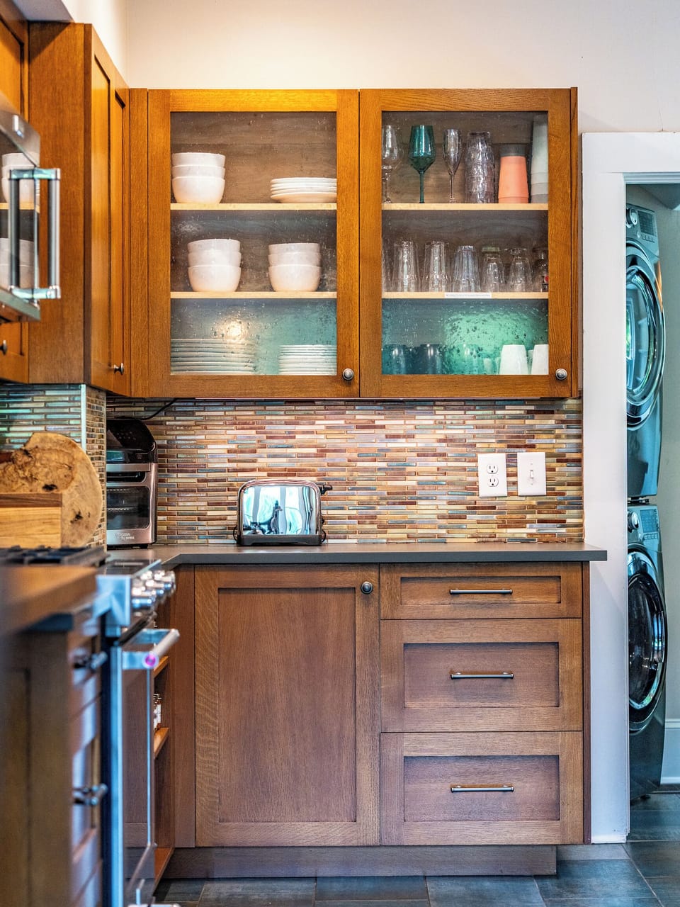 Warm kitchen with glass-front cabinets and in-unit washer/dryer