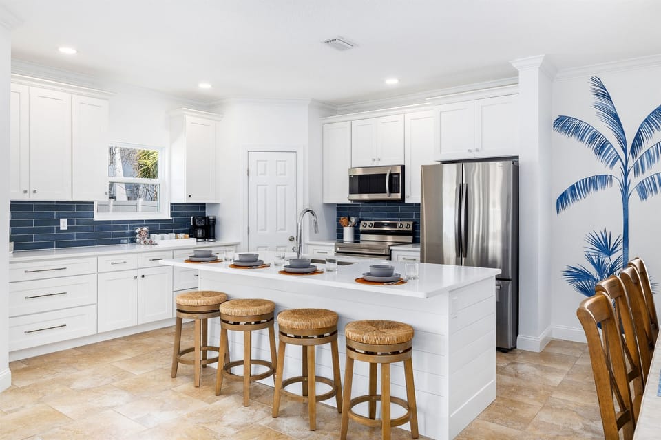 Beautifully renovated kitchen featuring quartz countertops, stainless steel appliances, and a spacious island with seating for four — ideal for gathering, cooking, and casual meals.