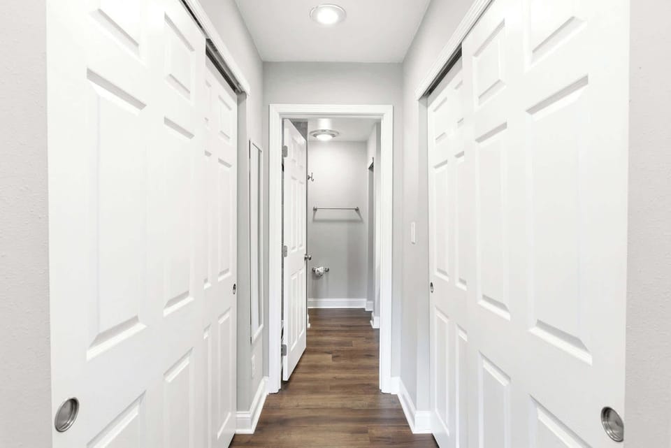 Dual sliding closet doors line the private hallway leading to the primary en suite — plenty of space for a full week's wardrobe.