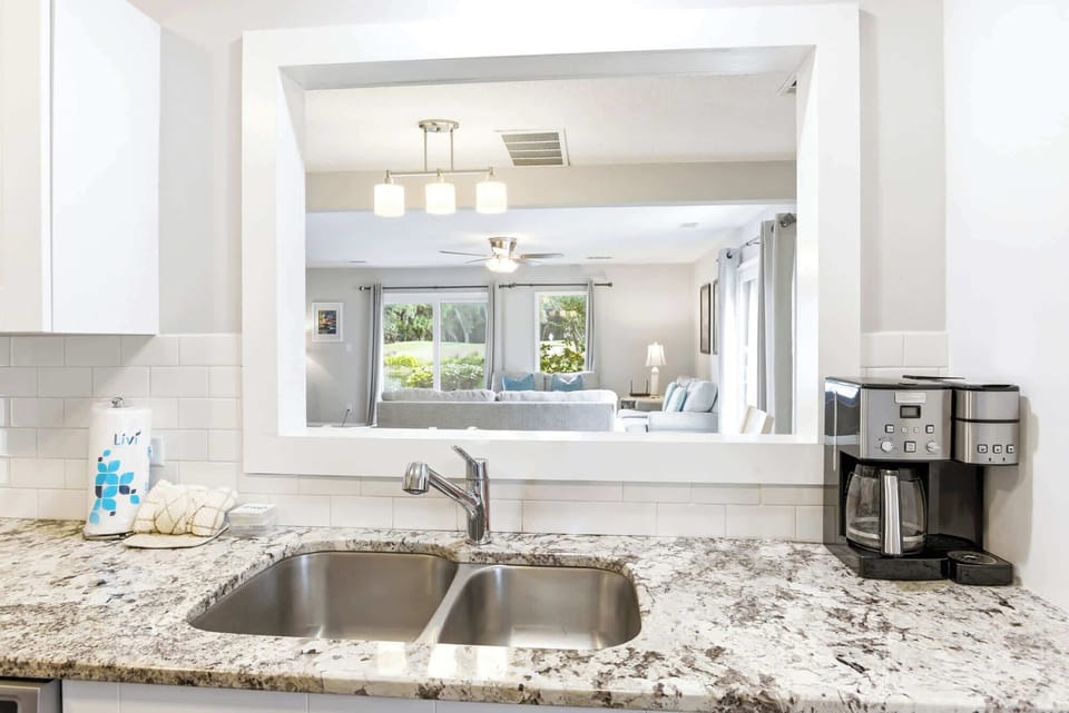 A wide pass-through window opens the kitchen to the living area, keeping the chef in the conversation while natural light flows through.
