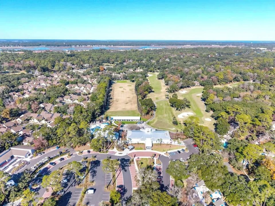 Aerial view showcases the resort's prime location near golf courses and wooded residential areas, with ample parking and easy access.