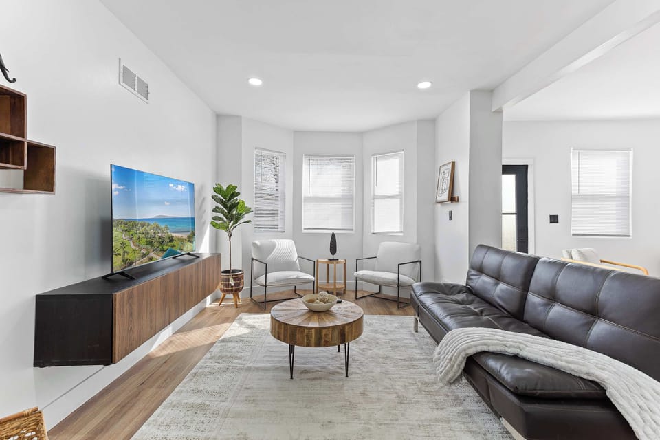 Bright open concept living area with comfortable seating, large windows, and Smart TV. Perfect for relaxing, entertaining, or accommodating extra guests with the sofa bed.