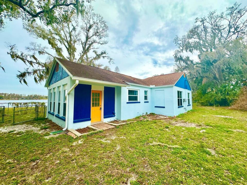 This charming teal lakeside ranch-style home blends vibrant character with laid-back waterfront living, offering the perfect backdrop for relaxing days by the water.