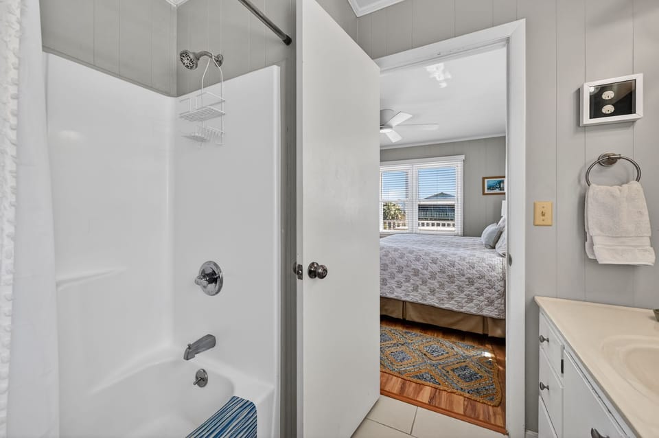 A view from the bathroom with a tub and shower into an adjacent bedroom.