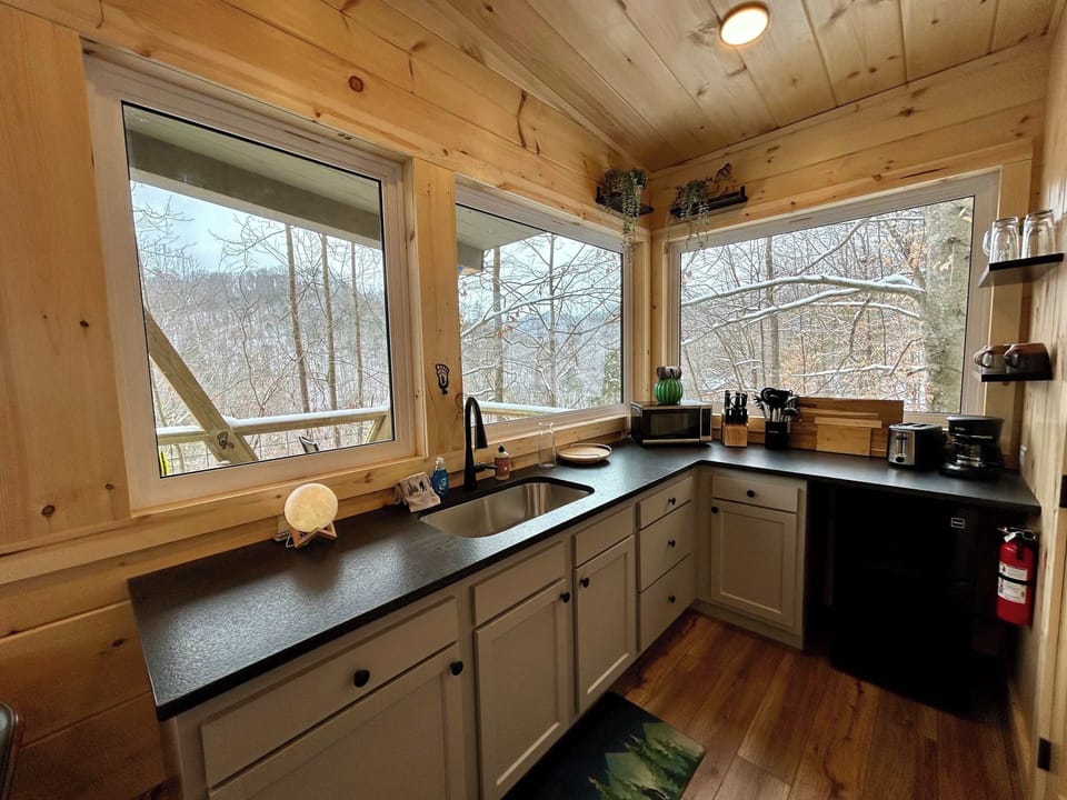 Sunlit countertops and large windows make this kitchen a peaceful place to start your morning. Thoughtfully designed and compact, it includes a mini fridge, microwave, and portable induction cooktops for easy, simple meals.