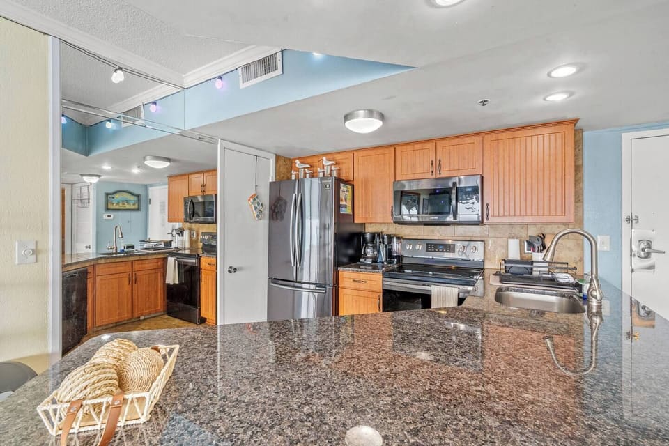 Beautiful kitchen with stone countertops, large bar area, and seating for three—perfect for enjoying a quick meal with an ocean view.