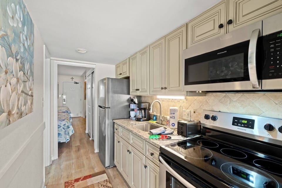 Fully equipped kitchen featuring stove, oven, microwave, refrigerator, Keurig and drip coffee maker, plus cabinet storage stocked with cookware, dinnerware, and silverware—everything needed for easy meals in Myrtle Beach.
