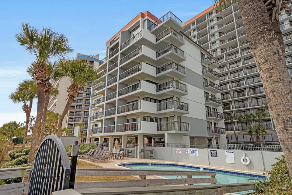 Palm-lined oceanfront exterior of Savoy at Grande Cayman, a classic coastal high-rise setting.