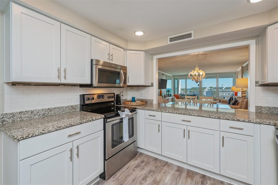 Cook with ease in your fully equipped kitchen, featuring granite counters and stainless appliances while enjoying ocean views.