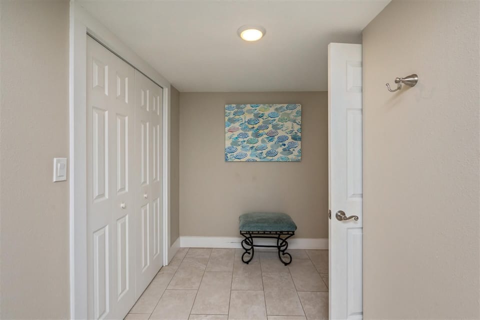 Step into your private retreat where ocean-inspired artwork and a cozy bench create a peaceful transition space before exploring your coastal getaway.