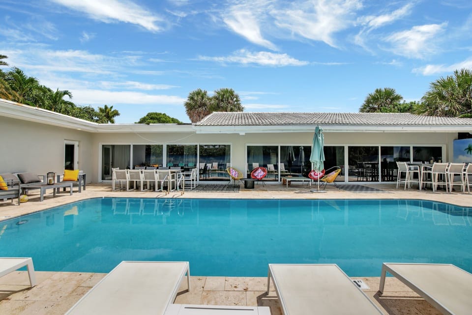 The house seen across the pool, with loungers on the deck.