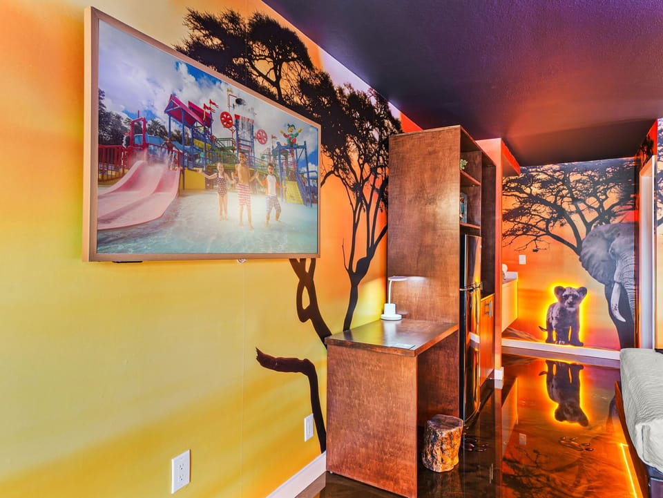 A vibrant room featuring wildlife murals and a mounted television for entertainment.